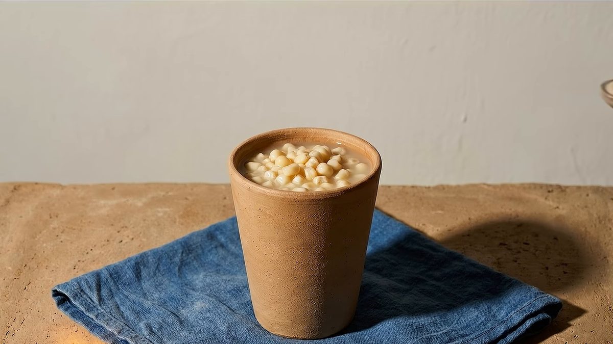 Vaso de barro lleno de esquites sobre un paño azul.