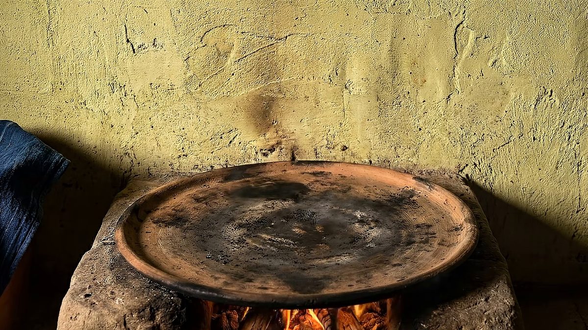 Comal de barro sobre un fogón encendido.